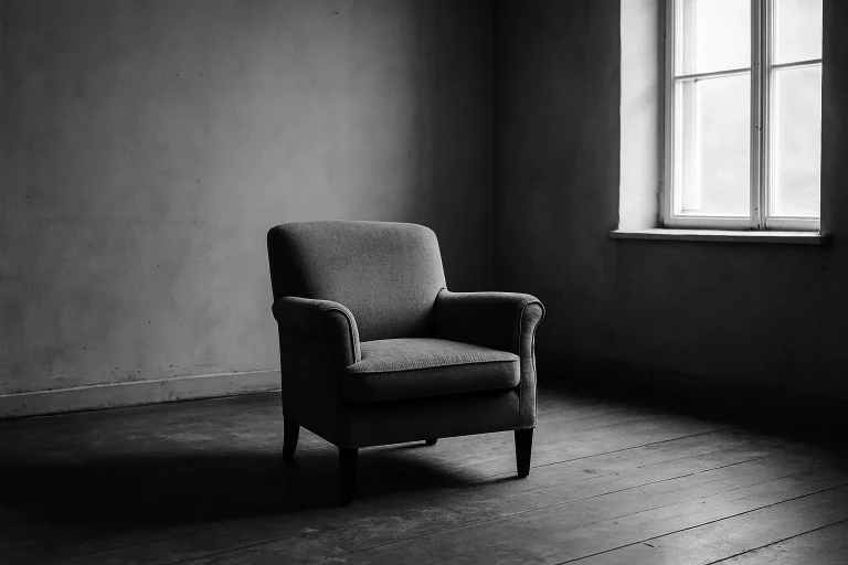 Une pièce vide et sombre en noir et blanc, avec un fauteuil central, éclairée par une fenêtre